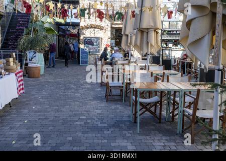 Denia, Alicante - Spanien - 12-22-2023: Gasse eines spanischen Marktes mit Restaurant mit leeren Tischen und zusammenklappbaren Sonnenschirmen, die auf Gäste warten Stockfoto