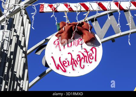 Denia, Alicante - Spanien - 22.12.2023: Hellblauer Himmel mit Weihnachtsschild „Frohe Weihnachten“ und roter Schleife Stockfoto