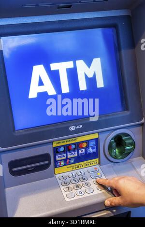 Denia, Alicante - Spanien - 22.12.2023: Person, die einen Geldautomaten benutzt, auf dem ein blauer Bildschirm mit großem „Geldautomat“-Text angezeigt wird Stockfoto