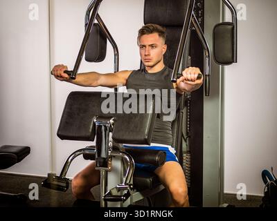 Muskulöser junger Mann, Training pecs auf Fitnessgerät Stockfoto