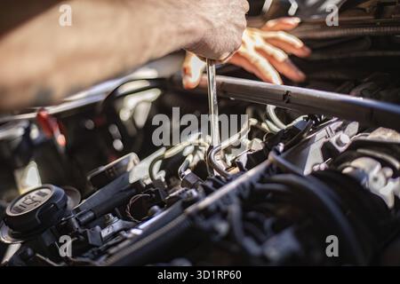 Nahaufnahme der schmutzigen Hände eines Mechanikers bei der Reparatur eines Automotors, wobei harte Arbeit gezeigt wird Stockfoto