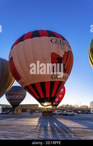 Guadix, Granada - Spanien - 24.01.2024: Ein großer rot-schwarzer Heißluftballon mit der Aufschrift GRANADA and GEOPARK wird für den Start gegen einen warmen Su vorbereitet Stockfoto