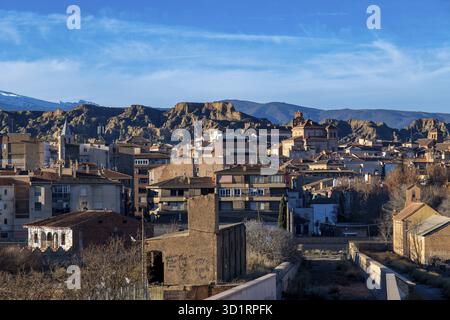 Guadix, Granada - Spanien - 01-24-2024: Ein Blick auf Guadix zeigt eine Mischung aus traditionellen und modernen Gebäuden im Vordergrund mit einem zerklüfteten Felsformat Stockfoto