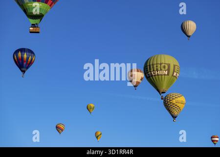 Guadix, Granada - Spanien - 24.01.2024: Mehrere bunte Heißluftballons steigen in den klaren blauen Himmel. Ein großer, grüner Euroküche-Ballon dominiert Th Stockfoto