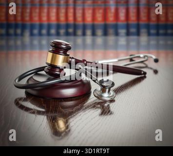 Hammer und Stethoskop auf Holztisch mit Gesetzbüchern im Hintergrund Stockfoto