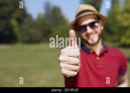 Lässige Jüngling Daumen auftauchen und lächelnd In den Park Stockfoto