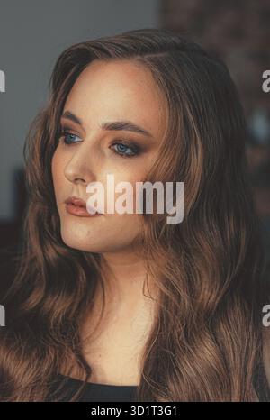 Schönes Brünette-Modell mit blauen Augen und perfektem Make-up, Mode-Schönheitporträt, das Transformation und strahlenden Charme unterstreicht Stockfoto