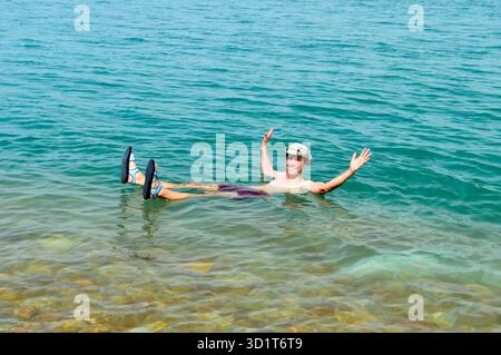 Porträt eines sorglosen Mannes, der seine Arme mit einem Sonnenhut auf toter Robbe ausstreckt Stockfoto