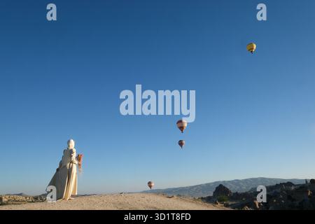 Frau, die Heißluftballons sieht, die am Himmel über einer einzigartigen Landschaft schweben, Kappadokien, Türkei Stockfoto