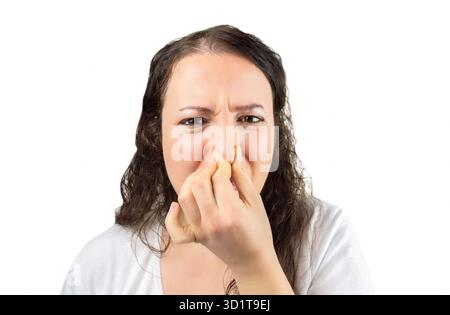 Zugeschnittenes Bild einer Frau, die ihre Nase und ihren Mund bedeckt, mit ihren Händen, die in die Kamera schaut, um Ekel zu sehen, und es gibt einen schlechten Geruch über einem weiß Stockfoto
