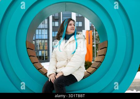 Frau, die auf der Bank vor der Skulptur sitzt Stockfoto