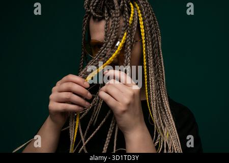 Frau mit Dreadlocks, die eine Brille hält Stockfoto