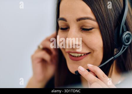 Benutzerfreundlicher Call Center-Agent, der eingehende Anrufe mit einem Headset entgegennimmt, das den Remote-Kundendienst bereitstellt. Stockfoto