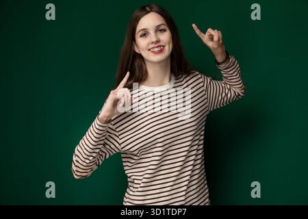 Frau in gestreiftem Hemd macht Friedenszeichen Stockfoto