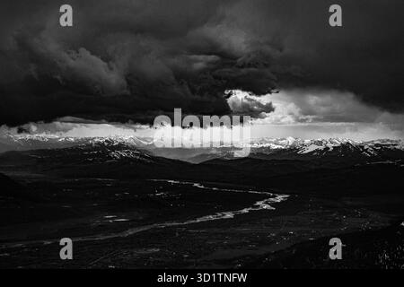 Schwarzweiß-Foto von Sturmwolken über der Grand Teton Bergkette in Wyoming, USA, mit einem gewundenen Fluss und schneebedeckten Gipfeln Stockfoto