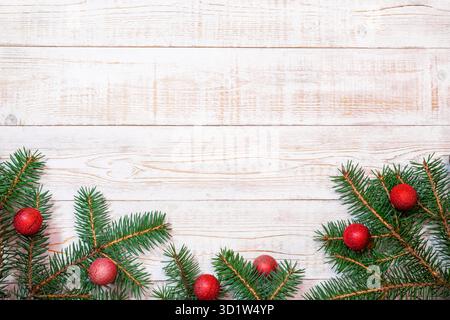 Weihnachtlicher Hintergrund - Tannenzweige und rote Ornamente auf einem weißen Holztisch. Flaches Layout, Rahmen für die Zusammenstellung von oben mit Kopierraum. Stockfoto