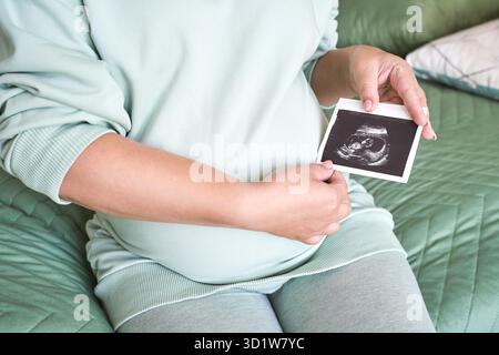 Schwanger Bauch mit Ultraschall Ergebnis Bild. Frau sieht ungeborene Kindergesicht Stockfoto