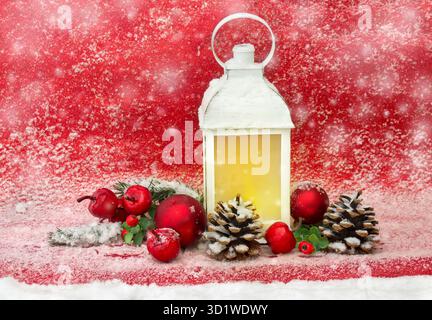 Weihnachtsdekoration. Weihnachtslaterne, rote Kugeln, Kegel, rote Äpfel, Brans Weihnachtsbaum auf rotem Glitzer Hintergrund bedeckt Schnee mit Platz für Text Stockfoto