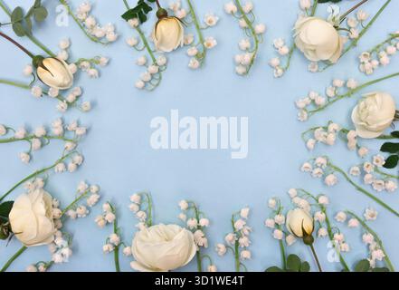 Weiße Blumen Lilie des Tales ( Convallaria majalis, Maiglocken, Maililie), weiße Rosen auf blauem Papierhintergrund mit Platz für Text. Draufsicht Stockfoto