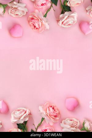 Rahmen von Blumen rosa Rosen mit Herzen auf einem rosa Papierhintergrund mit Platz für Text. Dekoration zum Valentinstag. Draufsicht, flach Stockfoto
