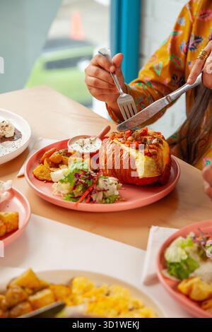Frau genießt Croissant-Sandwich-Frühstücksbrunch mit kaltem Eiskaffee. Stockfoto