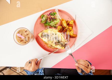 Arabische Frau genießt Brunch-Croissant-Sandwich mit Freunden in einem Restaurant. Stockfoto