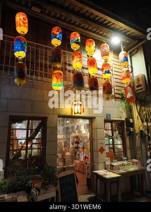 Tainan, Taiwan - 11. November 2024: Die Fassade eines historischen Gebäudes an der Shennong Street, heute ein Geschäft, dekoriert mit Reihen von bunten hängenden Laternen. Stockfoto