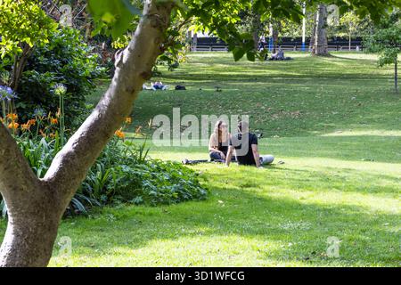 Friedliches Paar, das sich auf einem sonnigen Rasen in einem grünen Stadtpark entspannt. London, UK, 23. Juli 2023 Stockfoto