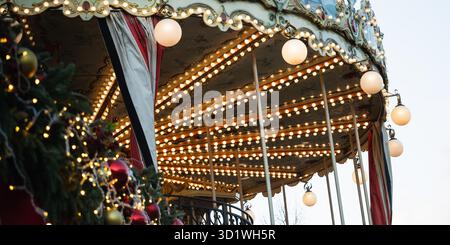 Weihnachtskarussell im Vintage-Stil mit Lichtergirlanden bei festlichen Feiertagen. Weihnachten genießen Sie in feierlicher nostalgischer Umgebung. Nahaufnahme. Stockfoto