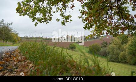 Panoramablick auf die Landschaft mit Feldern, Bäumen und einem fernen Dorf unter bewölktem Himmel. Herbstcharakter des ländlichen Europas Stockfoto