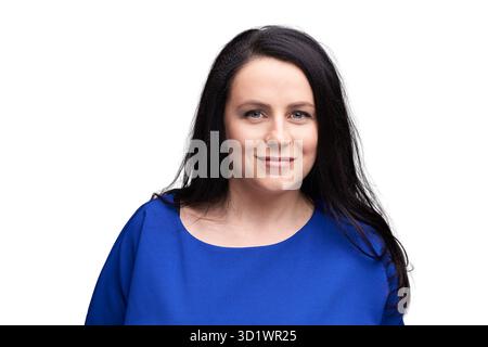 Selbstbewusste Frau in blauem Outfit lächelt vor weißem Hintergrund für Profis Stockfoto