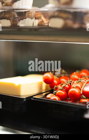 Käseblock und frische Kirschtomaten im Kühlschrank Stockfoto