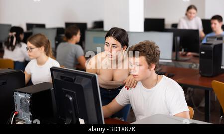 Teenager-Mädchen hilft Freundin, Probleme am Computer in der Schule zu lösen Stockfoto