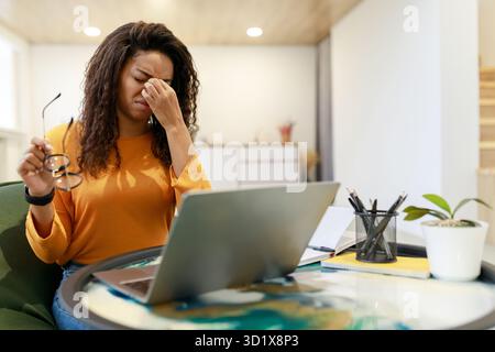 Frustrierte Frau, die am Schreibtisch arbeitet und mit Computerproblemen in heller Umgebung zu kämpfen hat Stockfoto