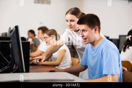Teenager-Mädchen hilft Freundin, Probleme am Computer in der Schule zu lösen Stockfoto