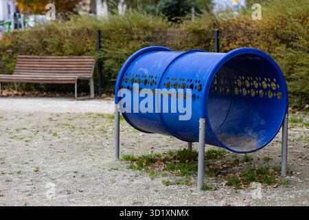 Outdoor Hundeschulungsspielplatz mit blauer Agility Tunnelausrüstung im öffentlichen Park am Herbsttag. Haustierübungen, Hundeaktivitäten und Gehorsamstraining Stockfoto