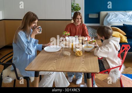 Eine glückliche Familie mit drei Eltern frühstückt zu Hause zusammen Stockfoto