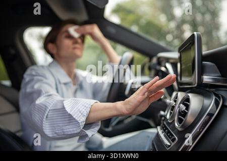 Frau fährt Auto mit kaputter Klimaanlage bei heißem Wetter wischt Schweiß auf Gesicht. Stockfoto