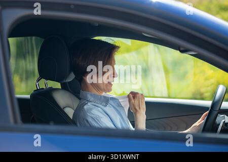 Frau fährt Auto mit defekter Klimaanlage und leidet an heißen Sommertagen an Hitze. Stockfoto