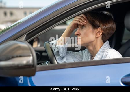 Müde unglückliche Frau sitzt im Auto, verärgerte Frau denkt an Eheprobleme, bevor sie nach Hause kommt Stockfoto