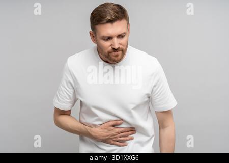 Unwohlsein Mann mittleren Alters, der an Verdauungsstörungen leidet und kranke Magenschmerzen berührt isoliertes Studio Stockfoto