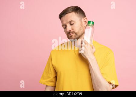 Ein müder Mann leidet an Hitze und Blutdruck, legt eine Flasche kaltes Wasser an den Hals, fühlt sich dehydriert. Stockfoto