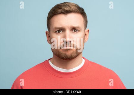 Porträt eines traurigen, frustrierten Mannes mittleren Alters mit Purpenlippen in Schwierigkeiten auf blauem Hintergrund. Stockfoto
