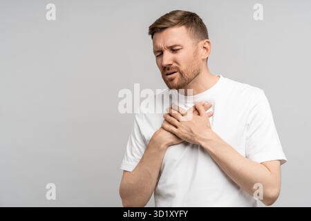 Der Mann hält sich an der Brust fest, leidet an Sodbrennen. Akute Beschwerden, Schmerzen im Brustbein. Stockfoto