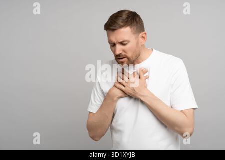 Der Mann hält sich an der Brust fest, leidet an Sodbrennen. Akute Beschwerden, Schmerzen im Brustbein. Stockfoto