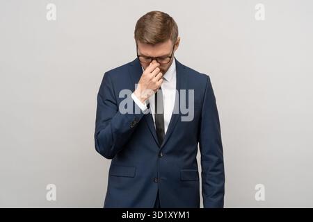 Herzzerreißter Geschäftsmann in Anzug, Büroangestellte sorgen sich vor grauem Hintergrund über den Verlust von Konkursjobs. Stockfoto