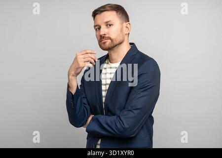 Erfolgreicher, selbstbewusster, gutaussehender Mann mittleren Alters mit festem Look und überkreuzten Armen im Studio Stockfoto