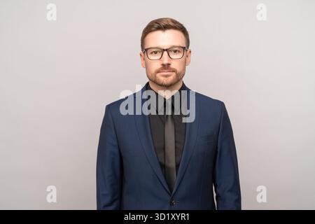 Erfolgreicher ernsthafter, selbstbewusster, gutaussehender Mann mittleren Alters, isoliert auf grauem Hintergrund, der in die Kamera schaut Stockfoto