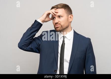 Müder, verwirrter, frustrierter Geschäftsmann im offiziellen Anzug mit unzufriedener Stirn Stockfoto