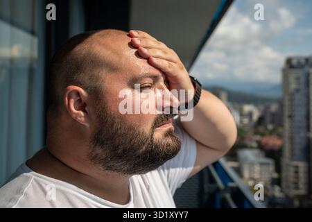 Porträt des übergewichtigen Mannes hat Kopfschmerzen, die Stirn berühren bei Hitze Sommerwetter. Stockfoto